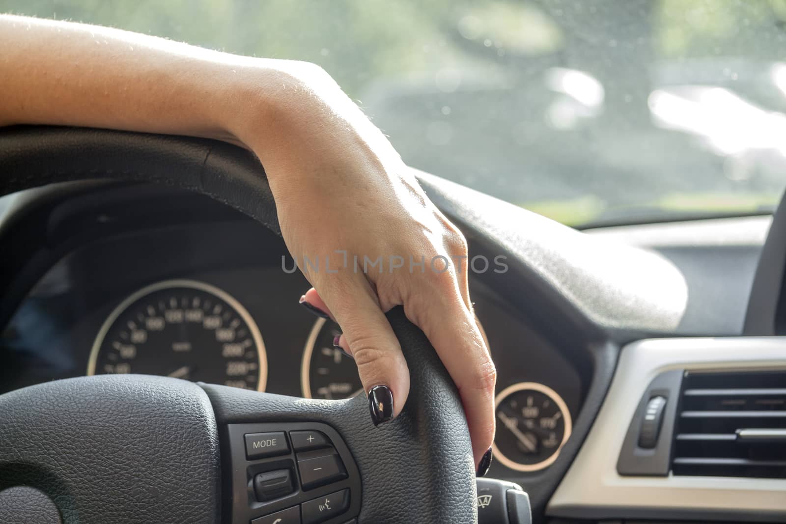 Arm girls with trendy manicure holds the steering wheel in the car.