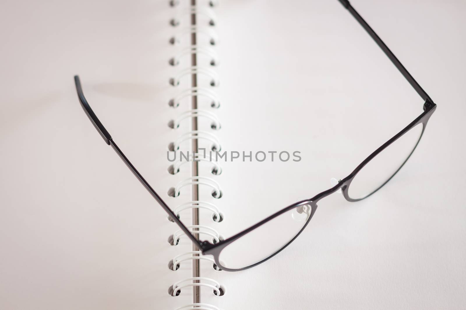Eyeglasses on opened spiral notebook , stock photo