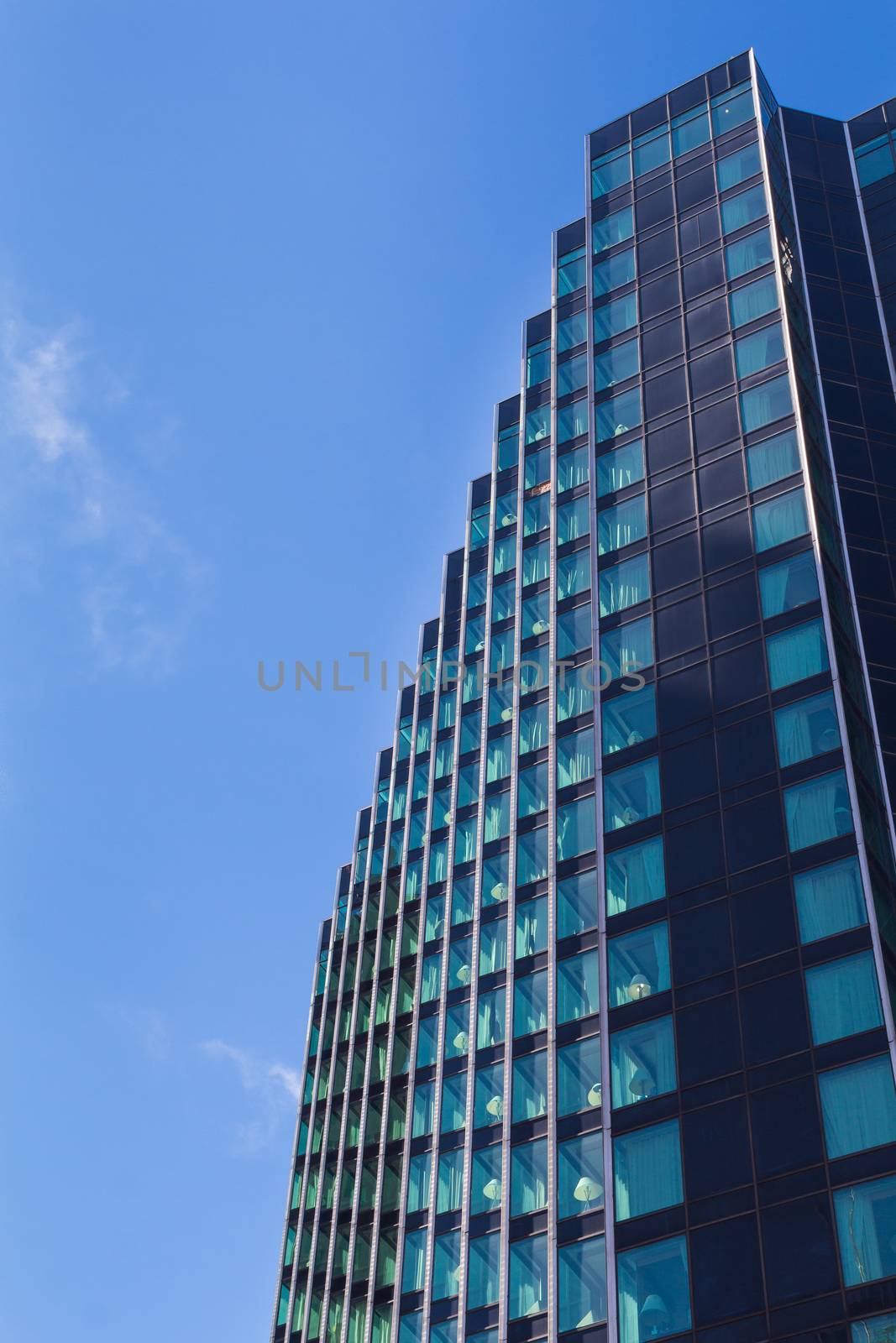 Detail of a modern skyscraper, which is reflecting the bright blue summer sky. Downtown Detroit, Michigan, USA