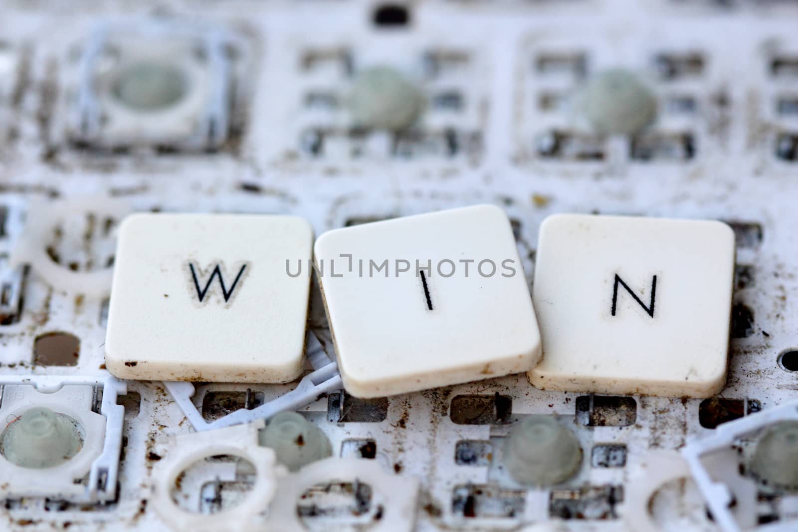 A close view of some keys on a dirty, yellowed keyboard.winner concept