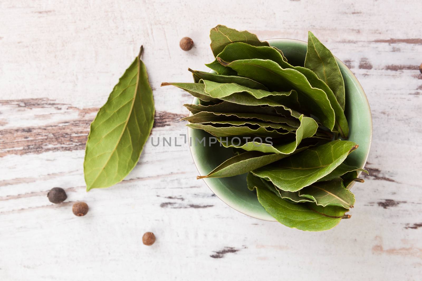Dry bay leaves on white wooden textured background. Culinary herb, cooking ingredient and medical herb. 