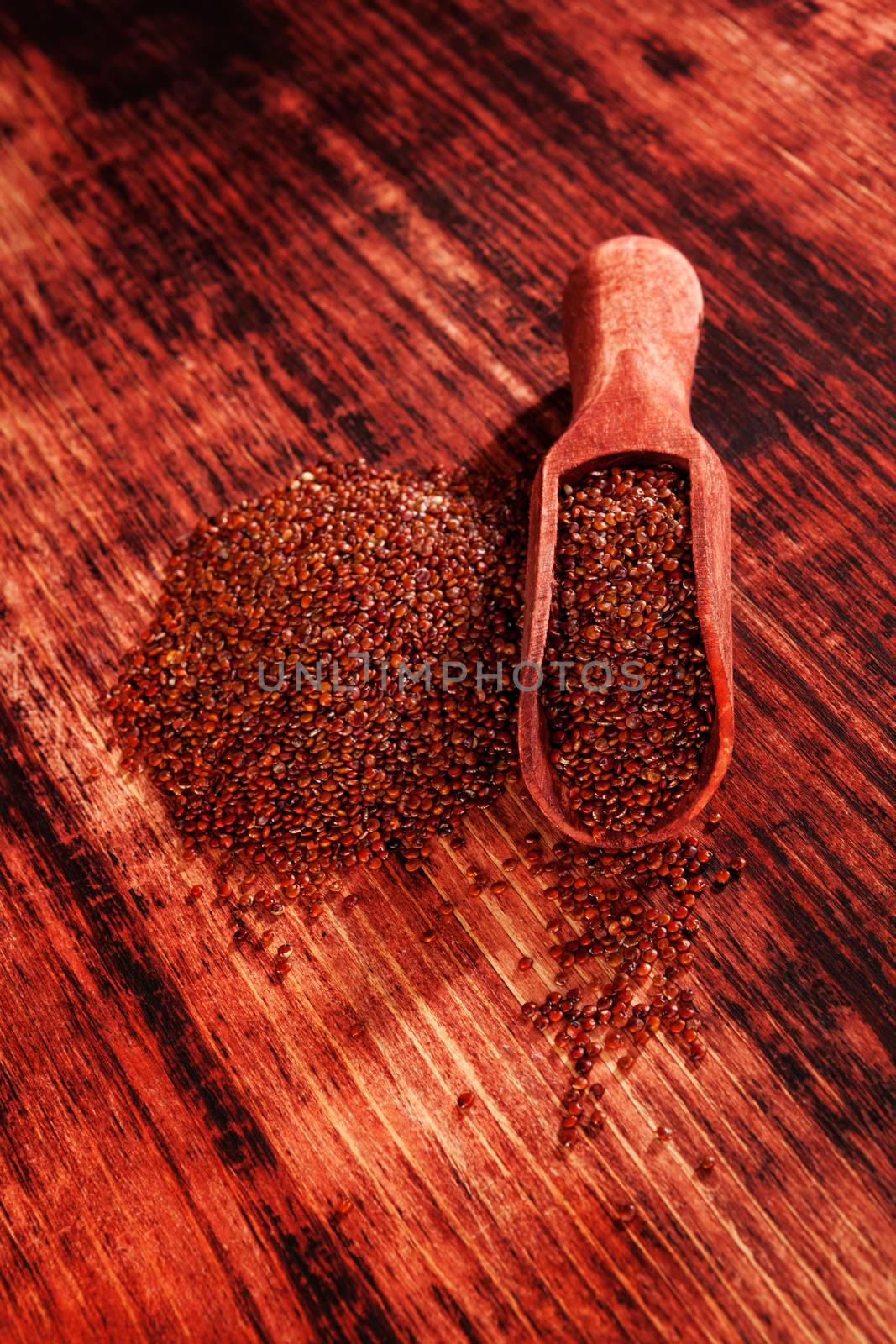 Red quinoa seeds on brown wooden table. Healthy eating.