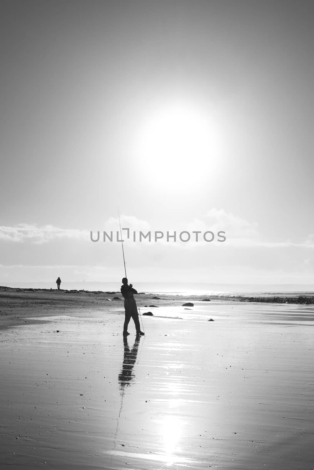 lone fisherman fishing on the sunset Kerry beach by morrbyte