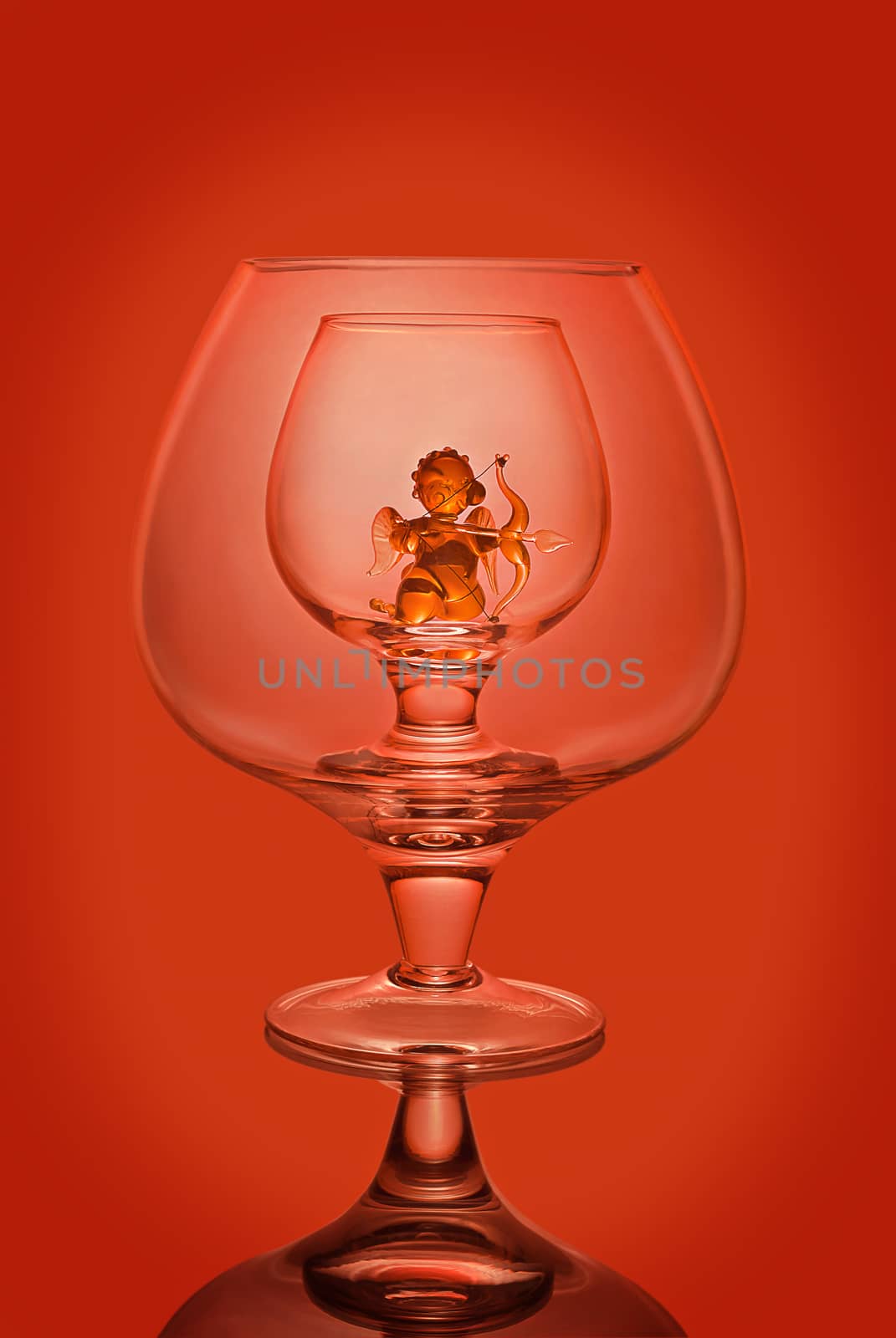 Empty wine glasses on a red background, a glass statuette of an angel inside.