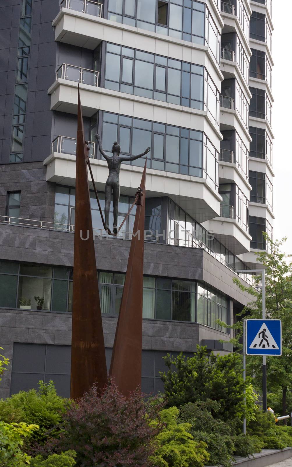 Metal ropewalker girl statue with an office building on the background