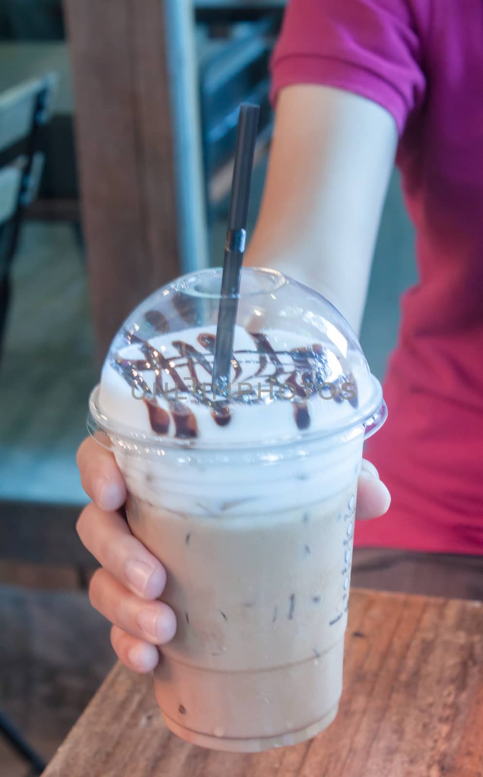 Take-home ice coffee cup on wooden table by punsayaporn