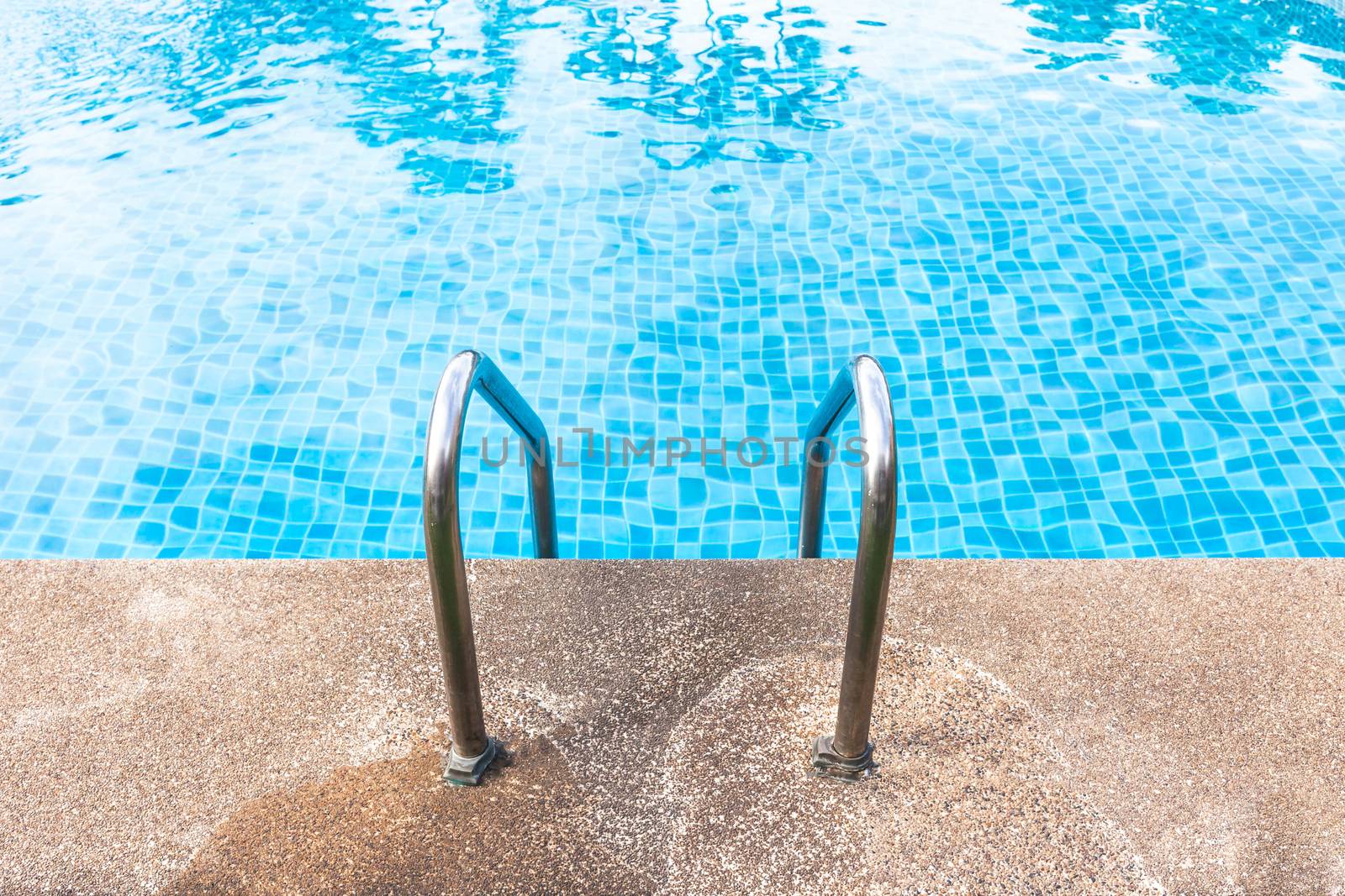 Staircase into the swimming pool with blue tiled. View from eye.