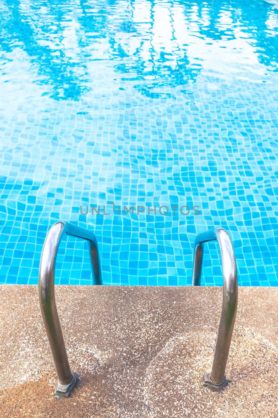 Staircase into the swimming pool with blue tiled. View from eye.