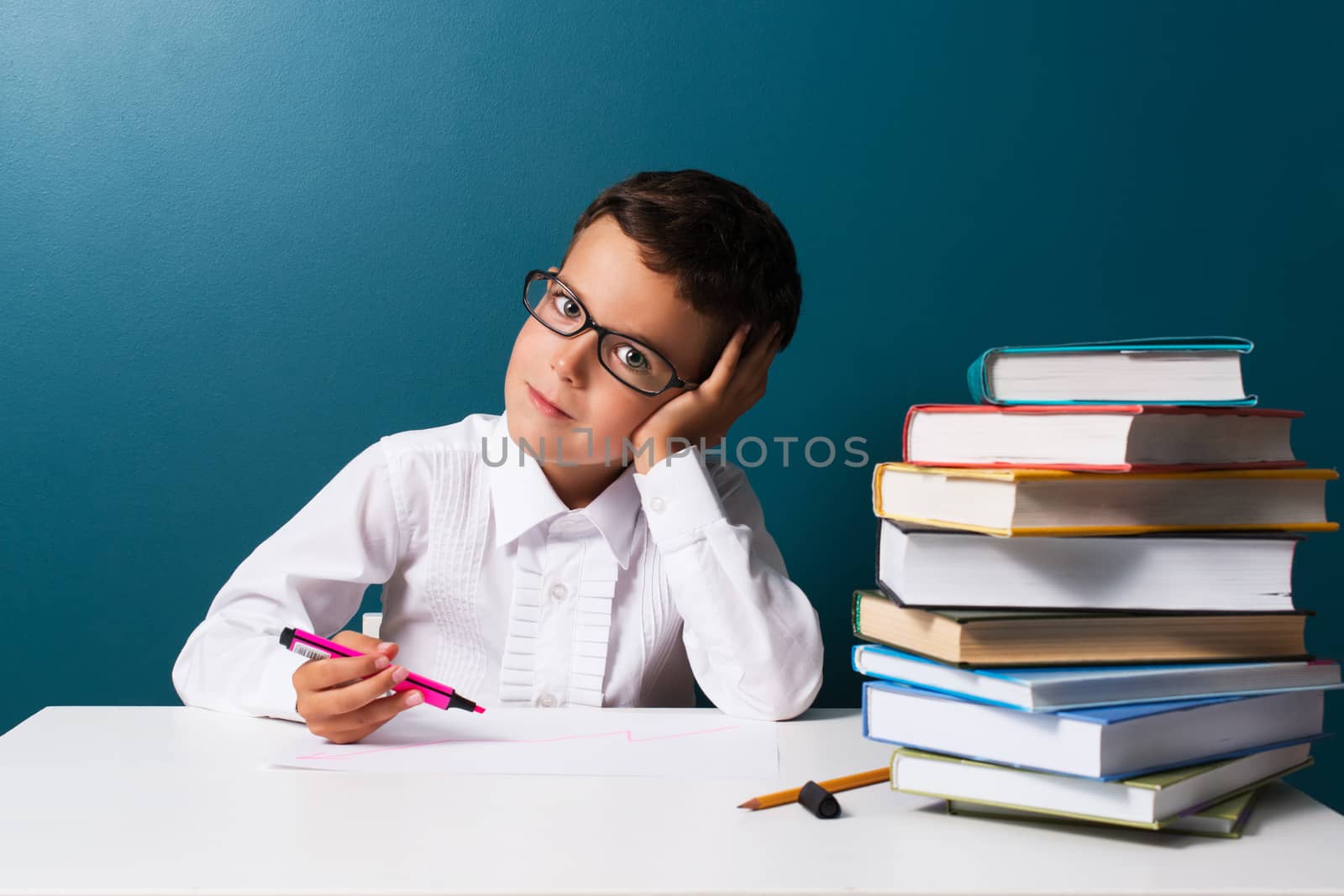 Pensive cute boy with glasses sitting at a table by kzen