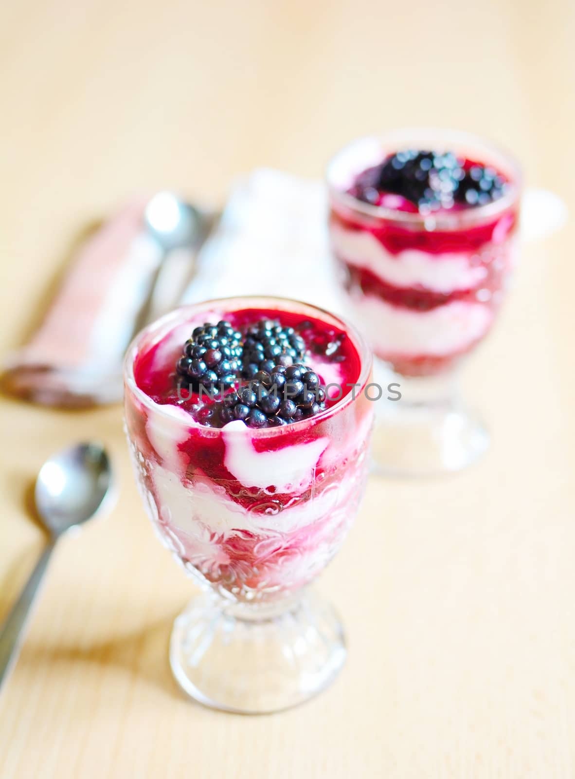 Glass cups with cream cheese blackberry desserts. Fresh blackberries are placed on top of the desserts.