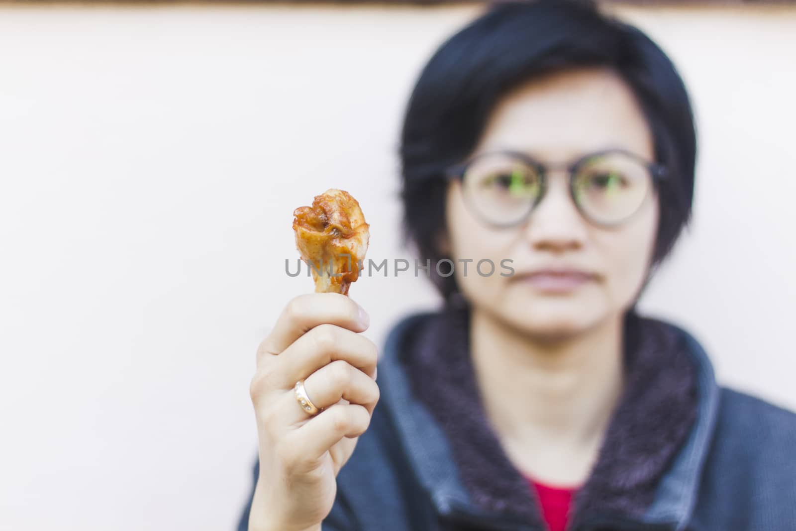Hand holding grilled chicken wing by punsayaporn