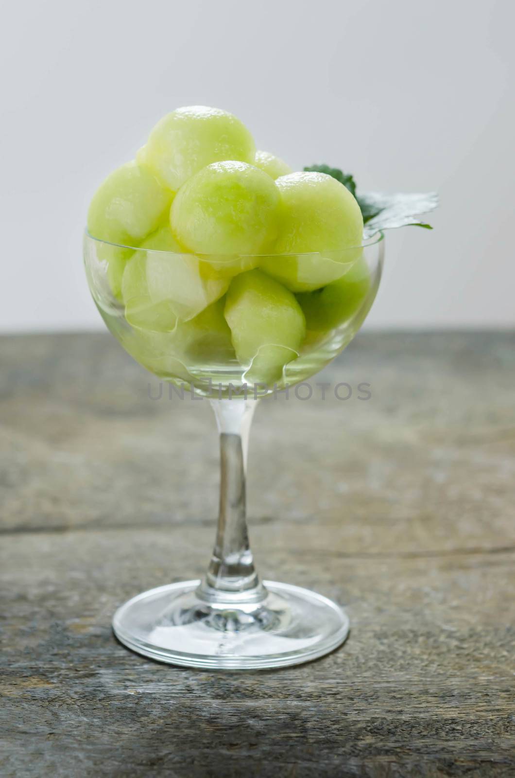 Fresh green cantaloupe melon in glass on wooden background