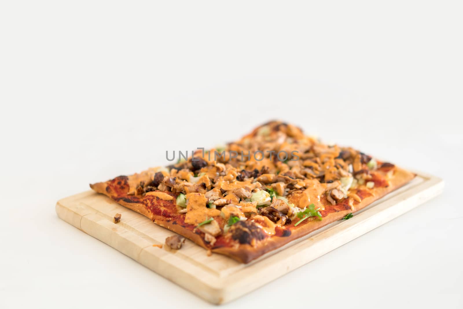 Homemade pizza on wooden plate, copy space on white table surface, depth of field effect