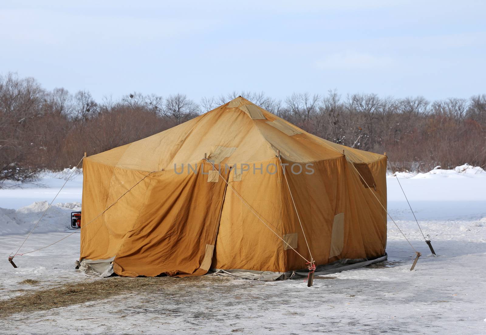 Military khaki tent in the snow polar region in a forest.