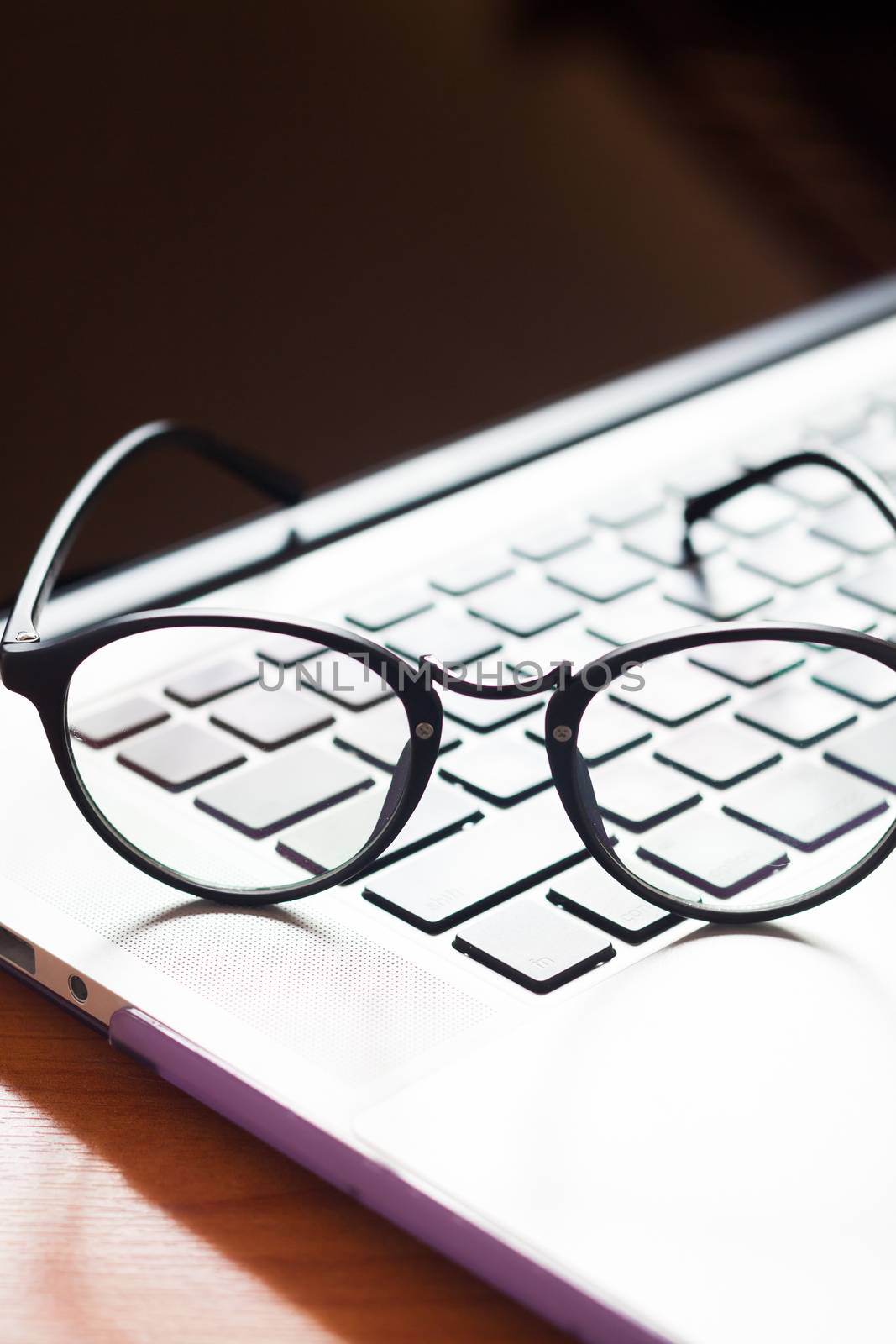 Workspace with eyeglasses on laptop, stock photo