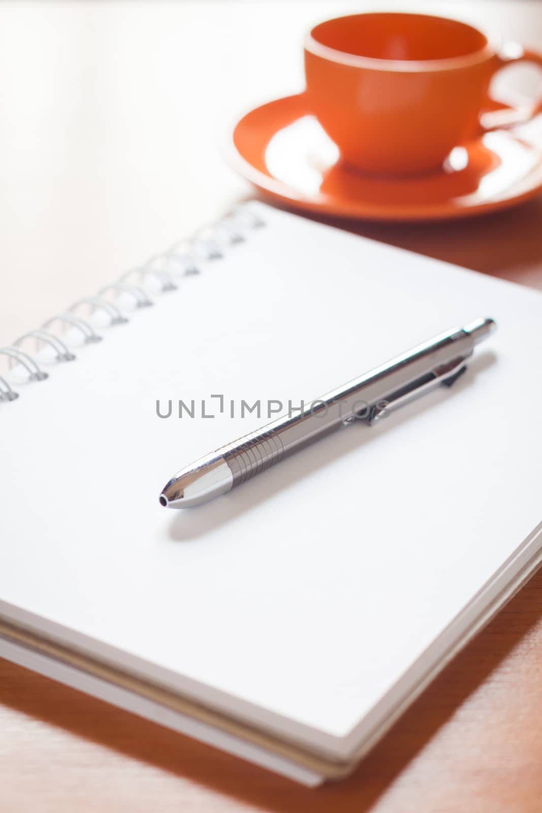 Pen on open blank white notebook with coffee cup on the desk, stock photo