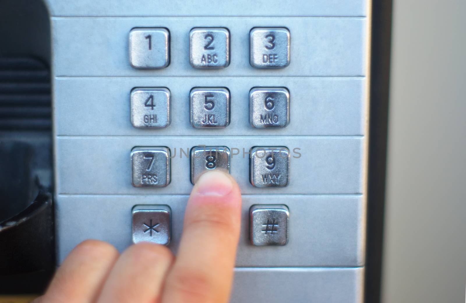 finger pushing telephone button public cabin, metallic buttons by jacquesdurocher