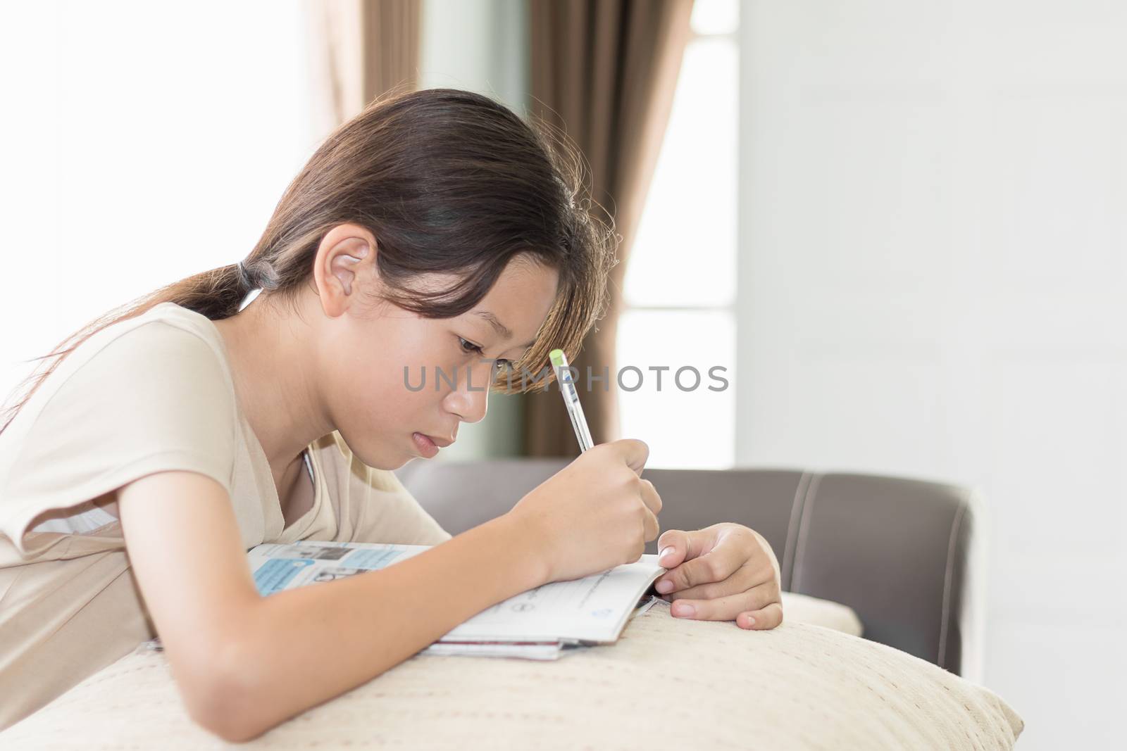 Asian girl doing her homework, writing on a lesson book