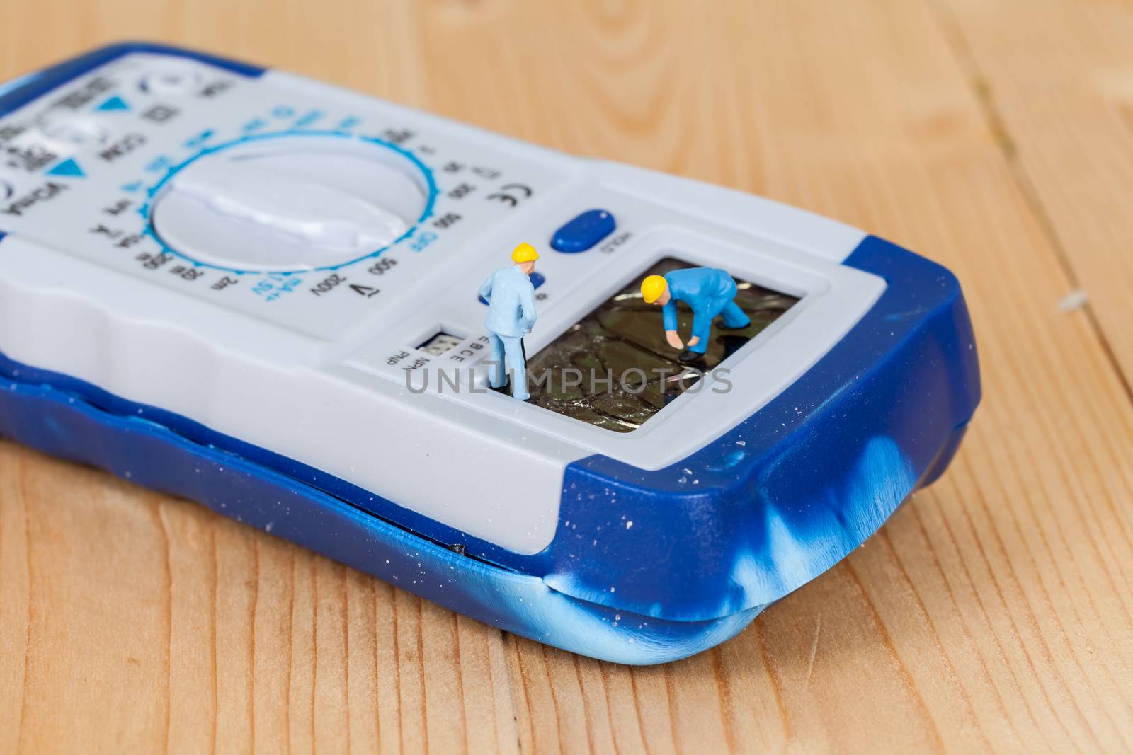 miniature maintenance team repairing a broken Digital multimeter