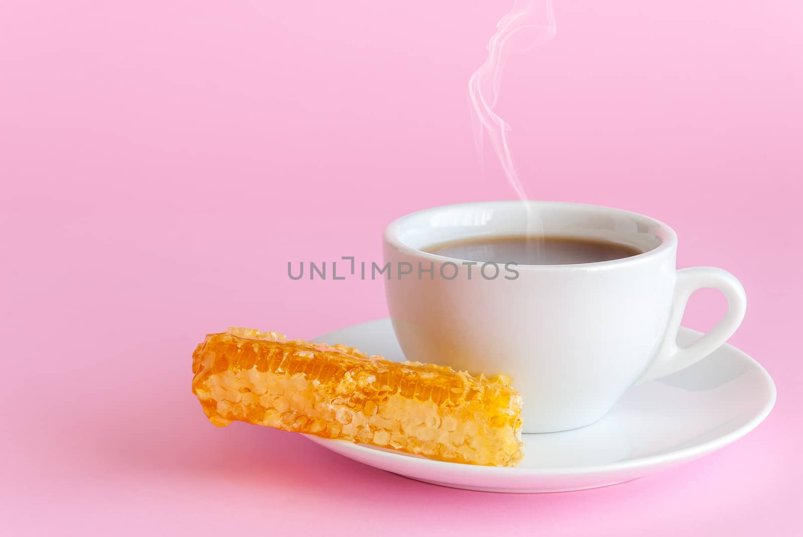 Cup of hot tea and honeycomb on pink background