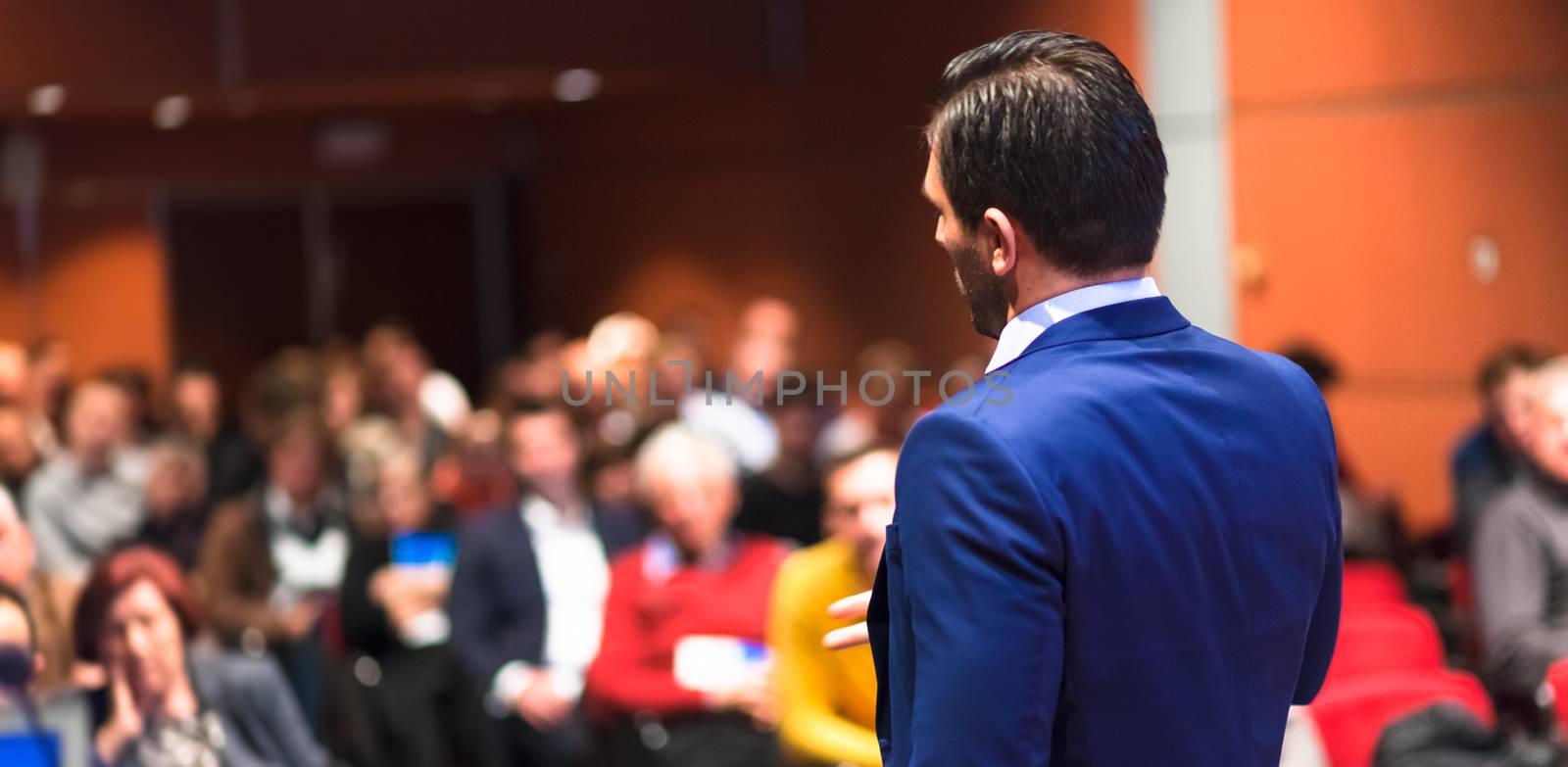 Speaker giving a talk on corporate Business Conference. Audience at the conference hall. Business and Entrepreneurship event.