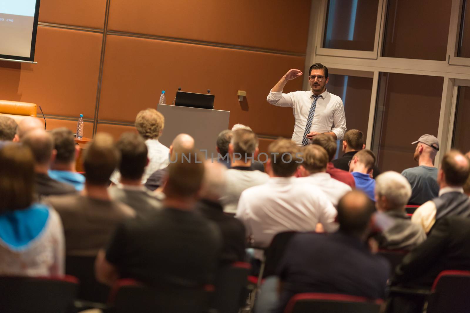 Speaker giving a talk in conference hall at business event. Audience at the conference hall. Business and Entrepreneurship.