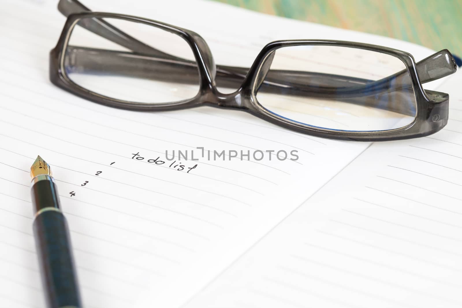 writing to do list on notebook page with pen on wood background