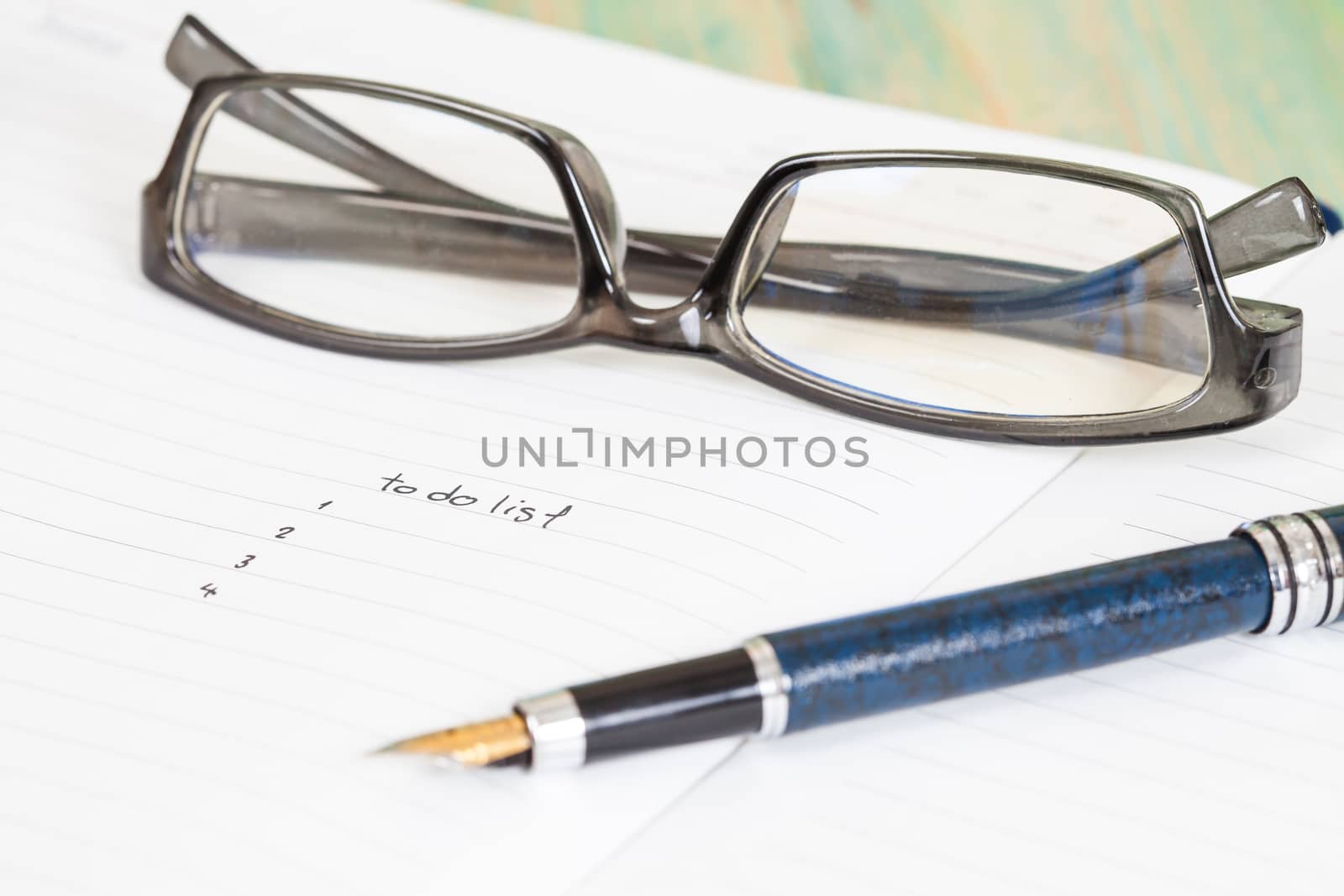 writing to do list on notebook page with pen on wood background