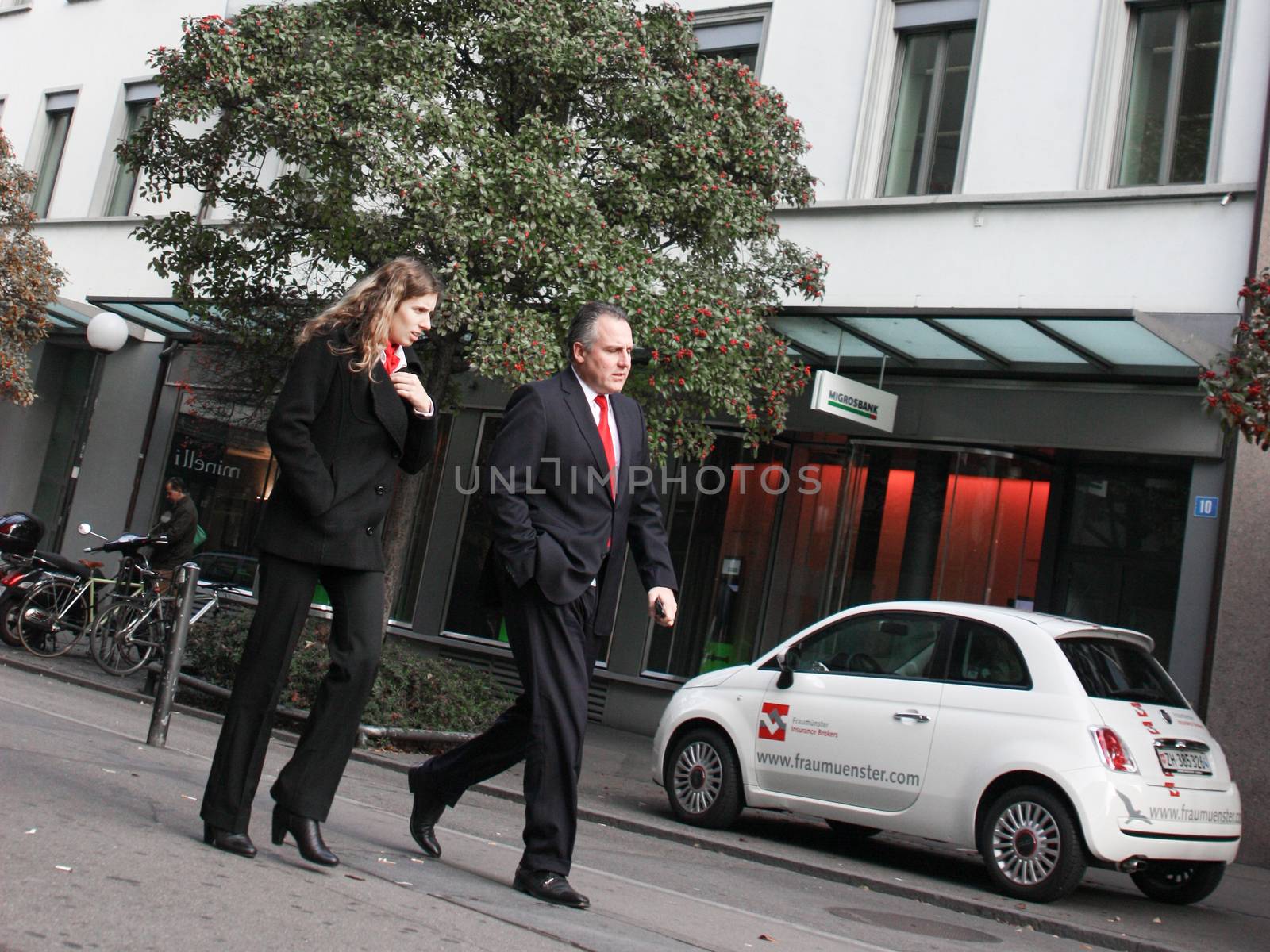 Zurich, Switzerland - November 27, 2011.  Business man and woman in expensive suits striding down the street.