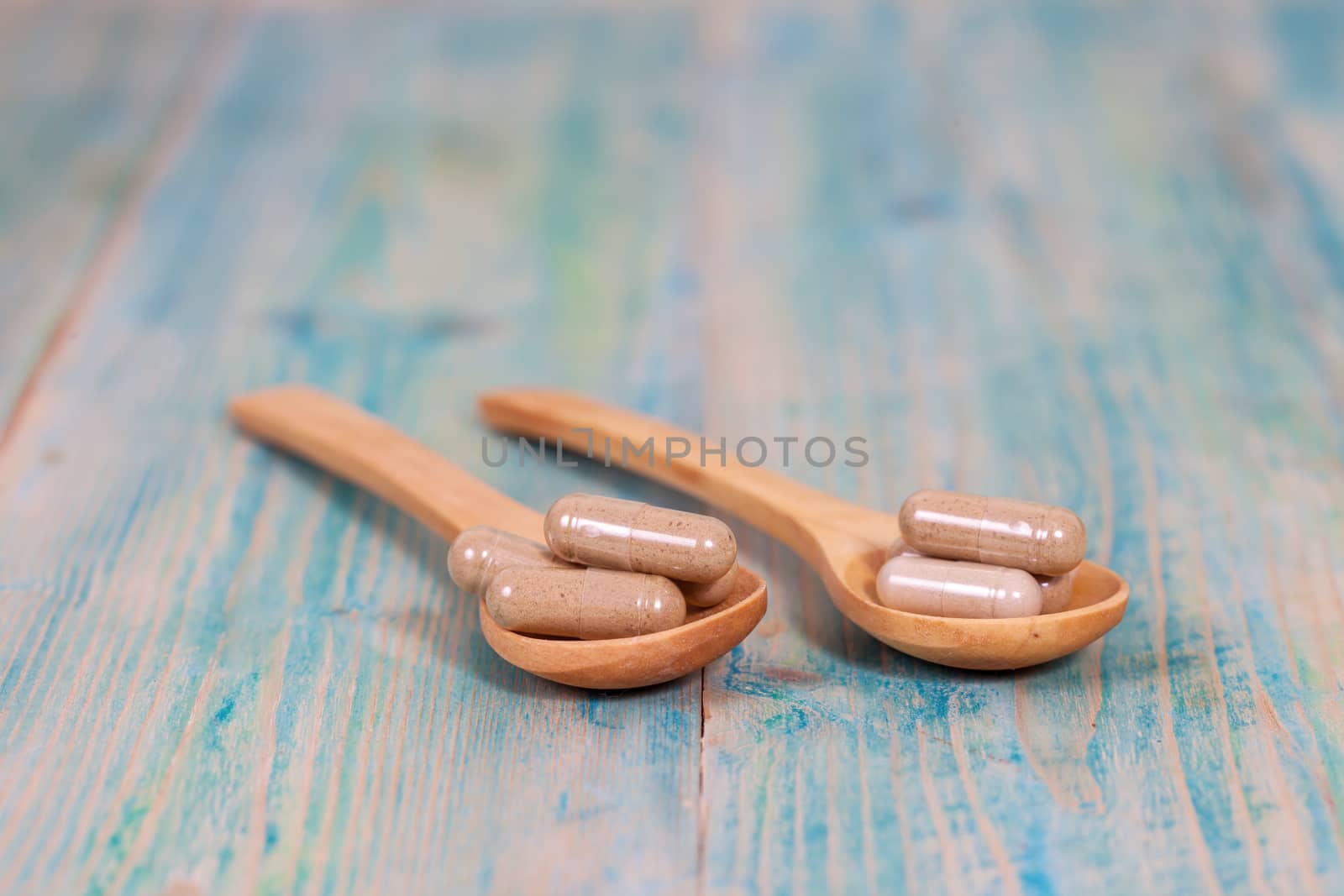 Capsules of herbs on spoon. healthy eating for healthy living.
