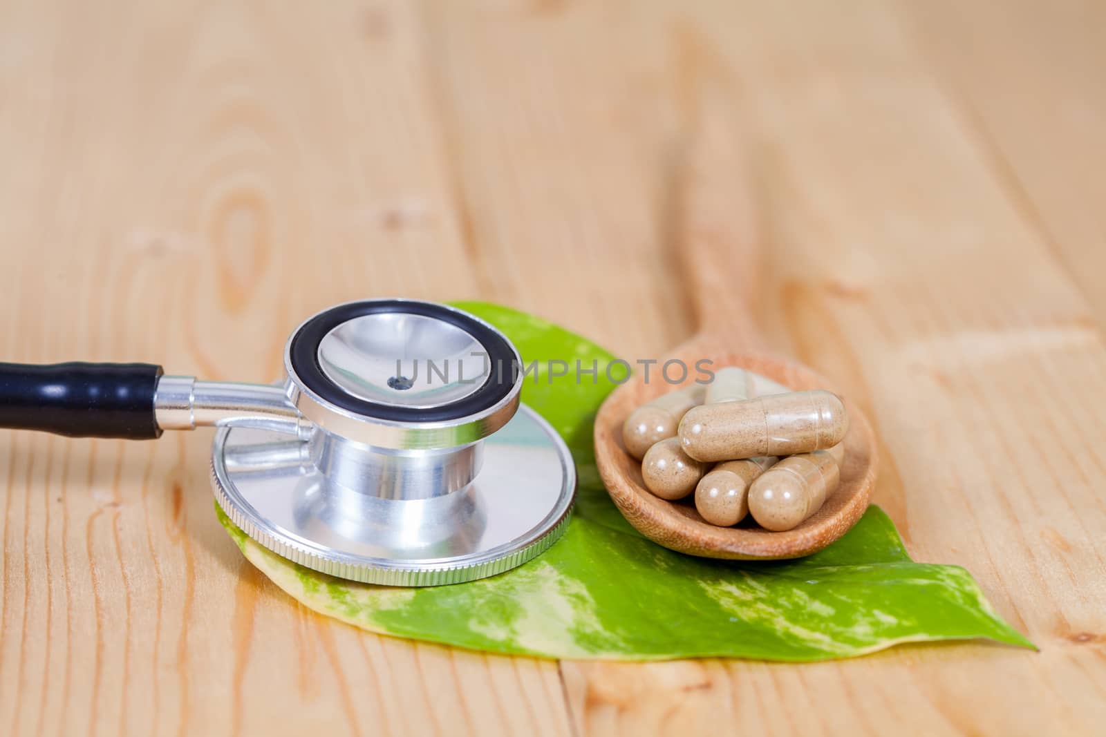 Capsules of herbs on spoon and stethoscope