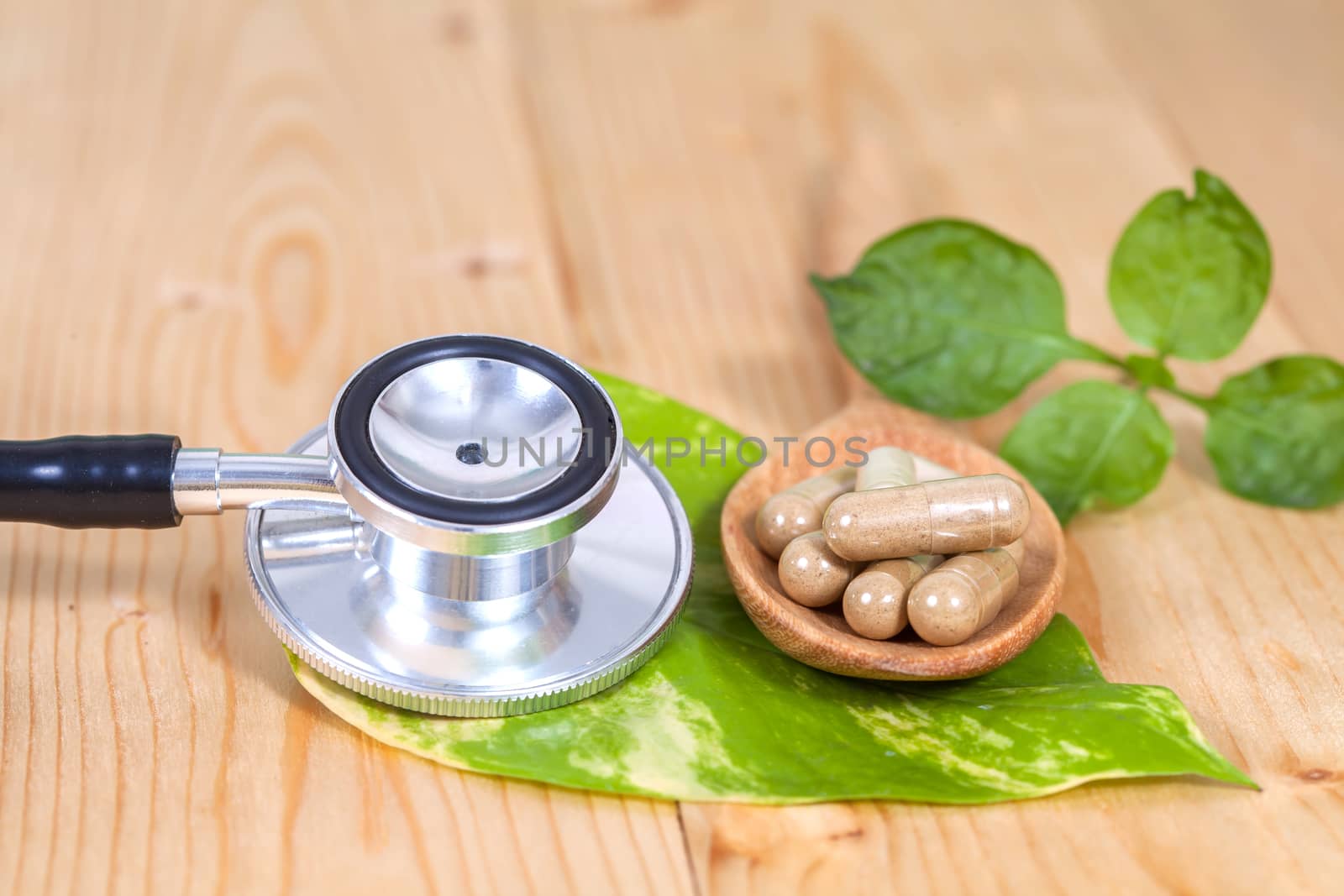 Capsules of herbs on spoon and stethoscope