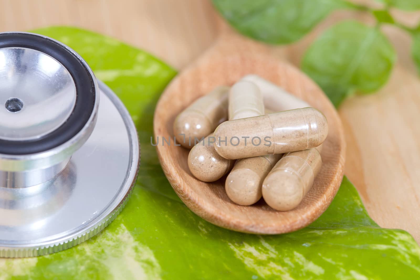 Capsules of herbs on spoon and stethoscope
