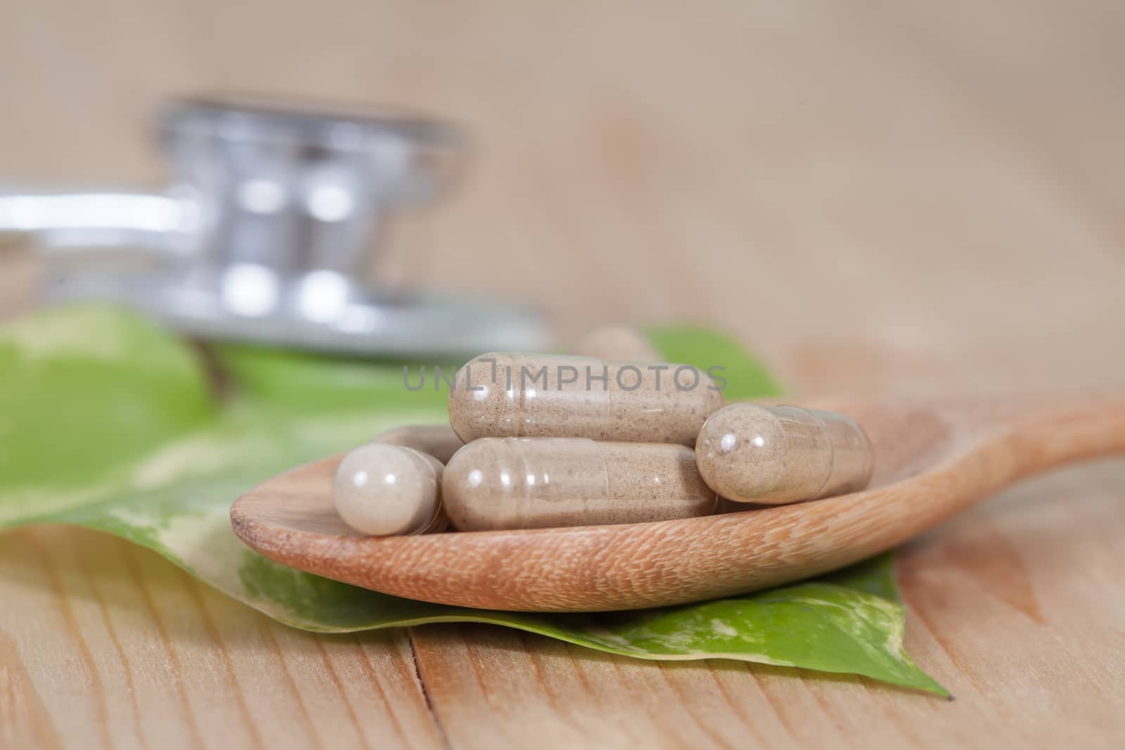 Capsules of herbs on spoon. healthy eating for healthy 
living.
