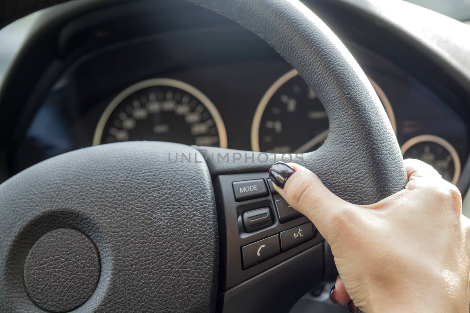 Arm girls with trendy manicure holds the steering wheel in the car.