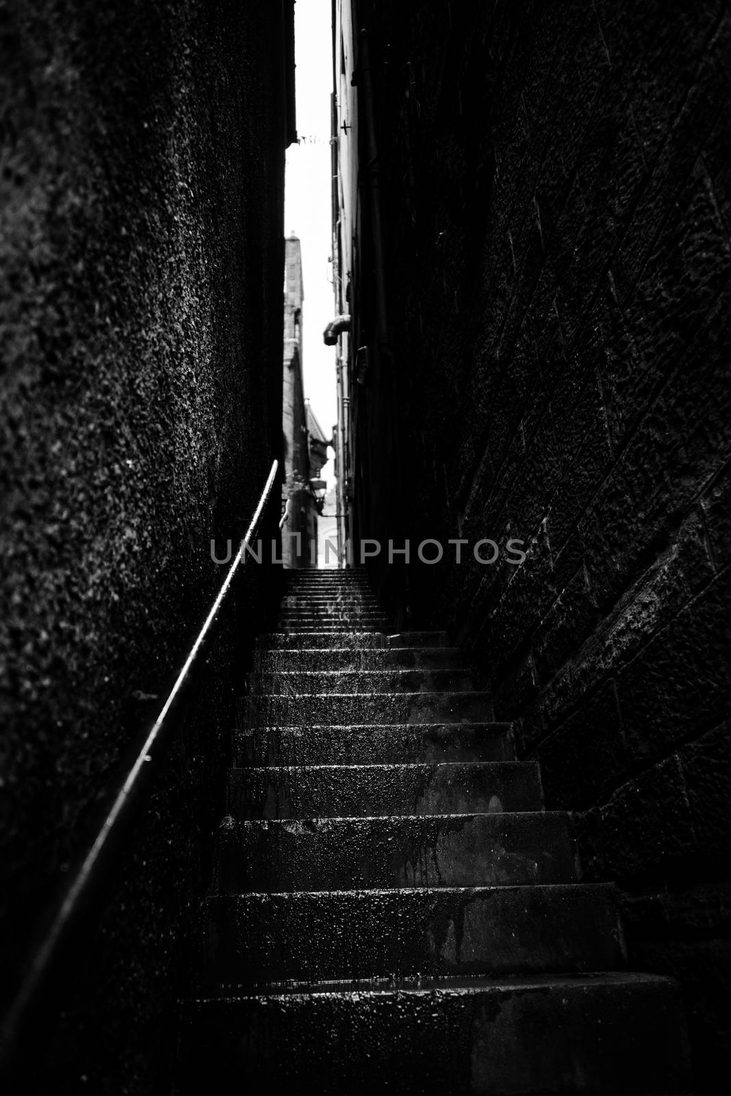 Narrow stairs between two high walls by a rainy day, black and white