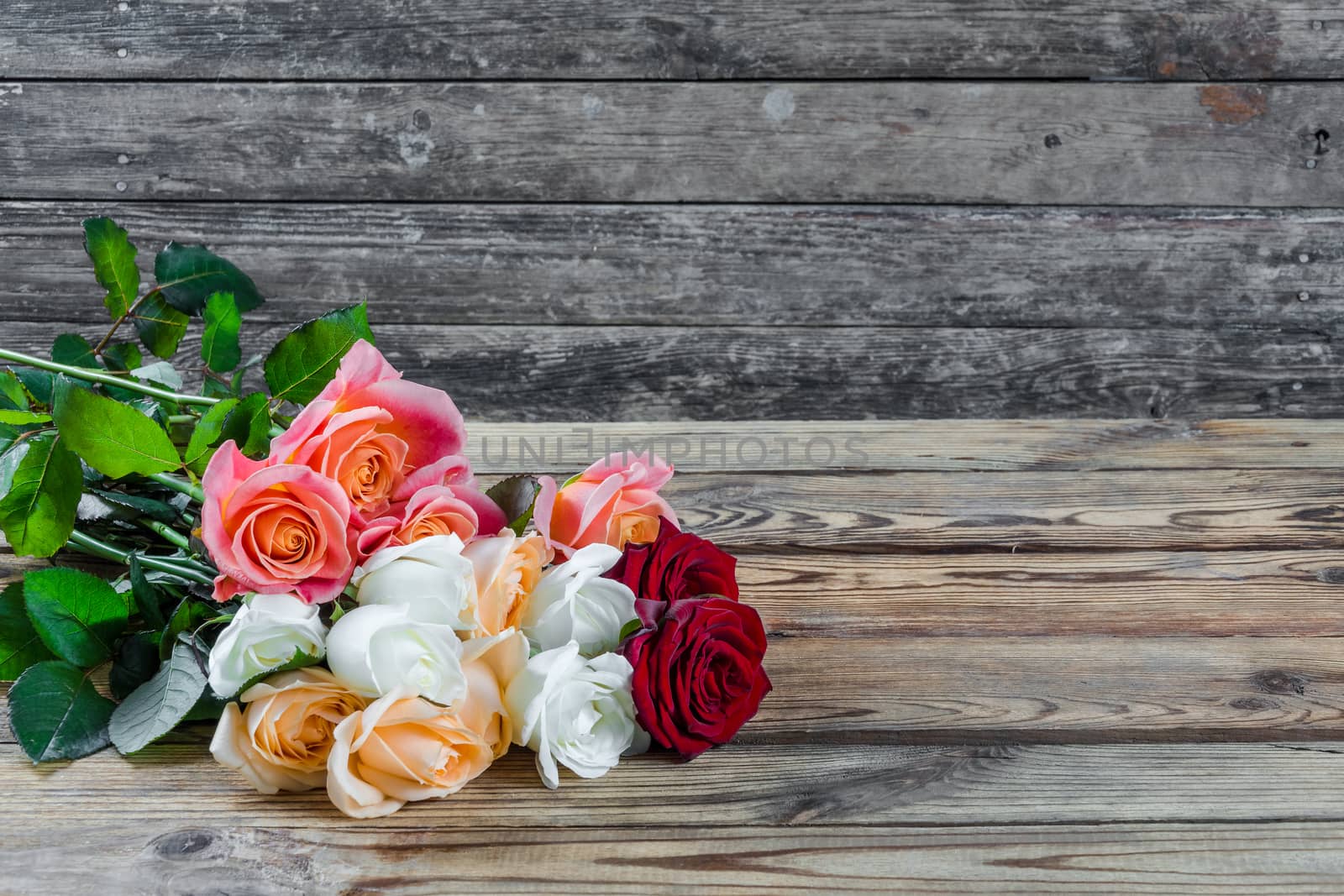 Beautiful bouquet of flowers roses on rustic wooden table