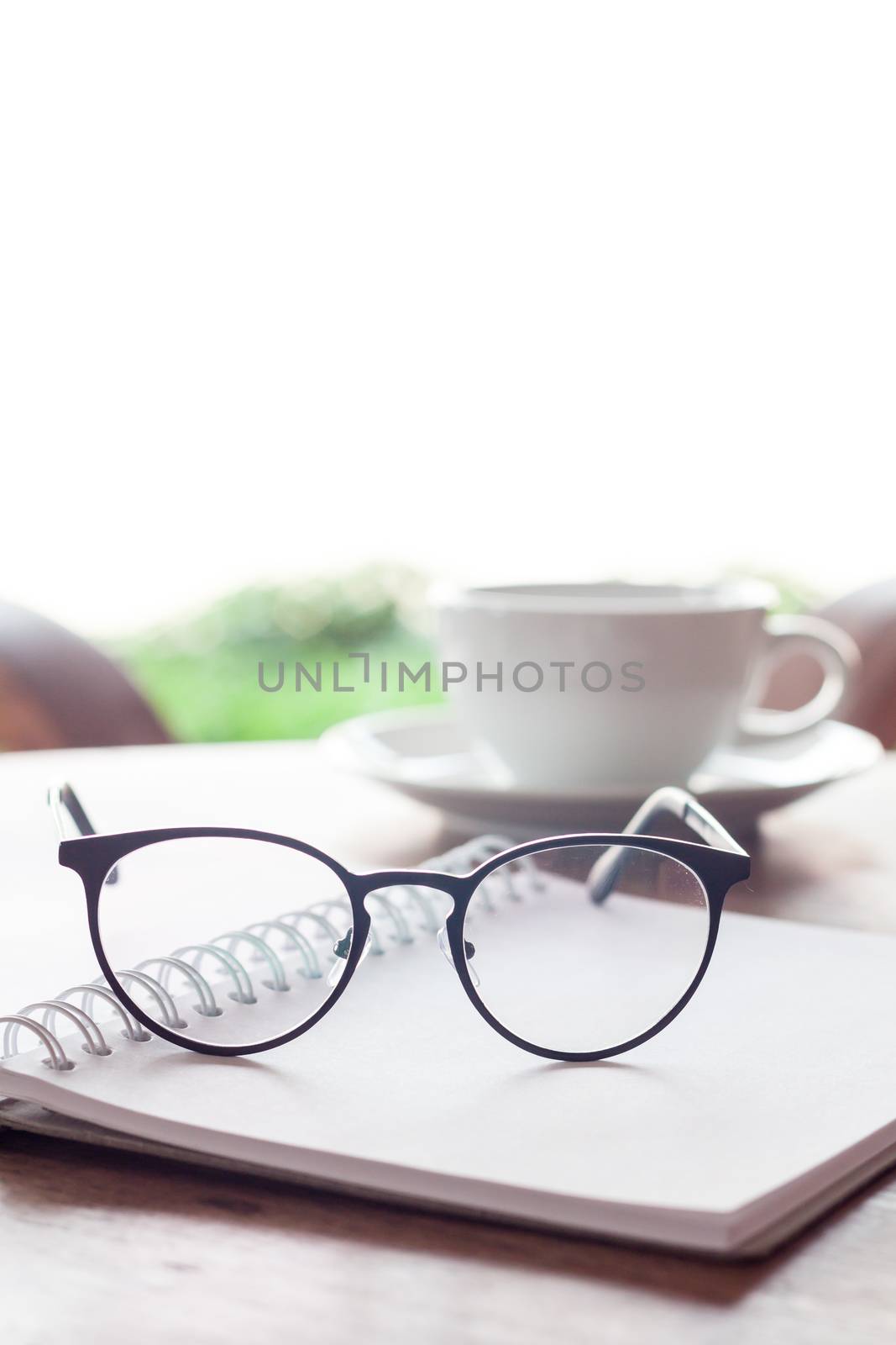 Open blank white notebook and eyeglasses with cup of coffee, stock photo