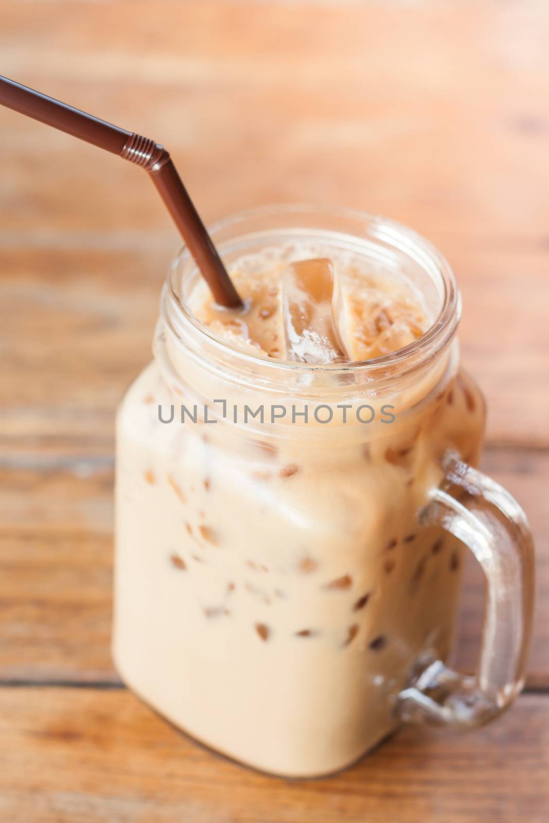 Glass of iced coffee on wooden table with vintage filter style by punsayaporn