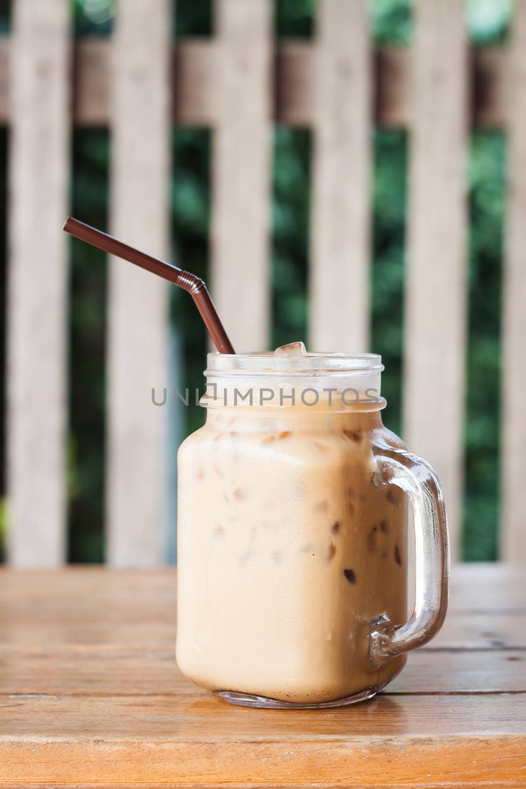 Glass of iced coffee on wooden table with vintage filter style, stock photo