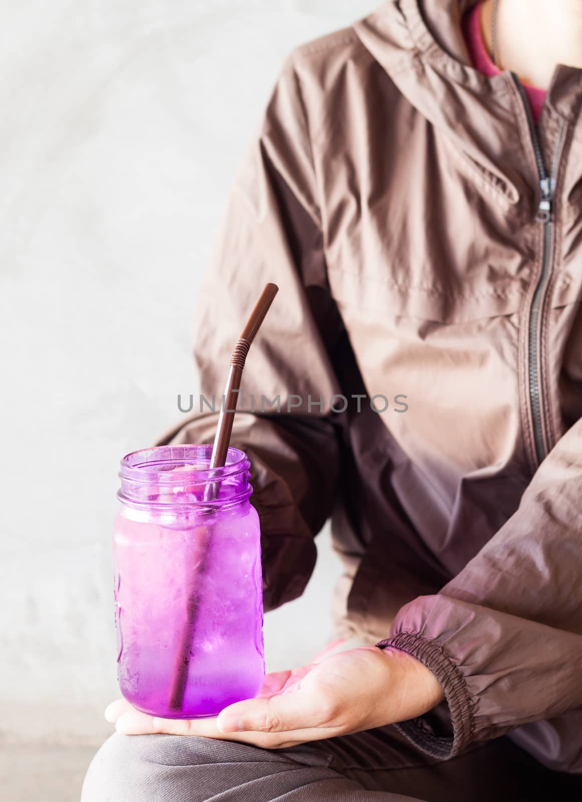 Woman hand holding iced drink in violet glass with vintage filter,  stock photo