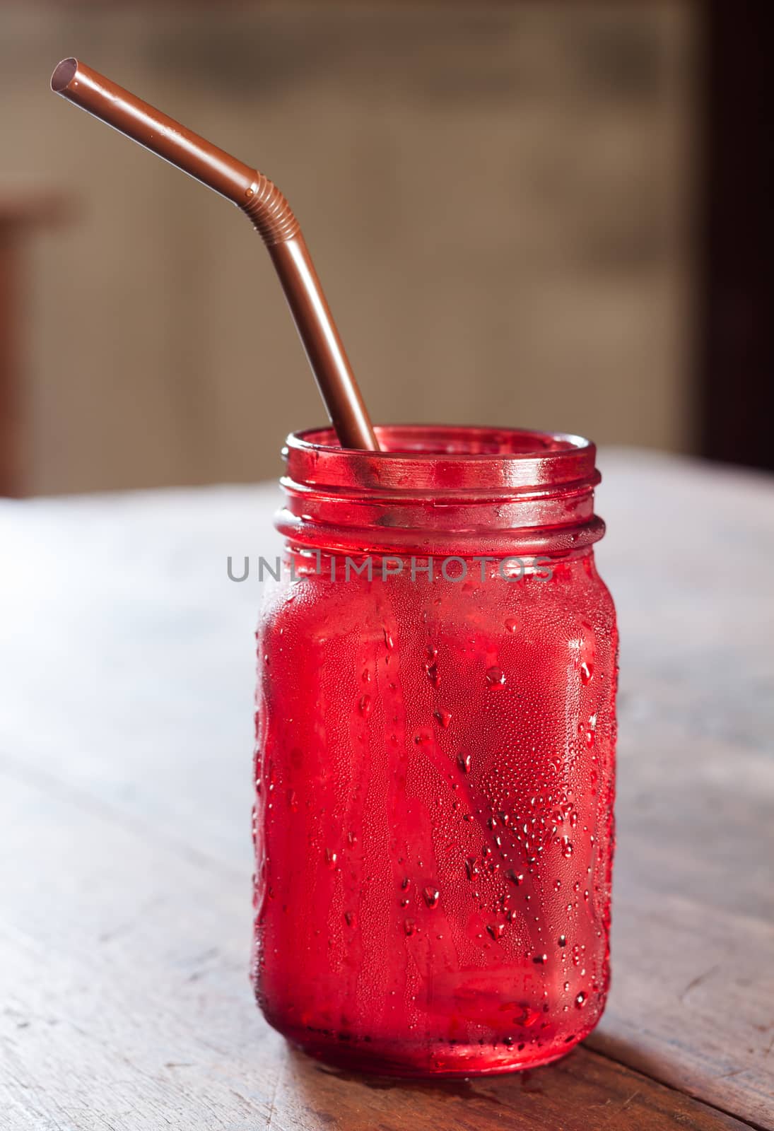 Iced drink in red glass on wooden table by punsayaporn