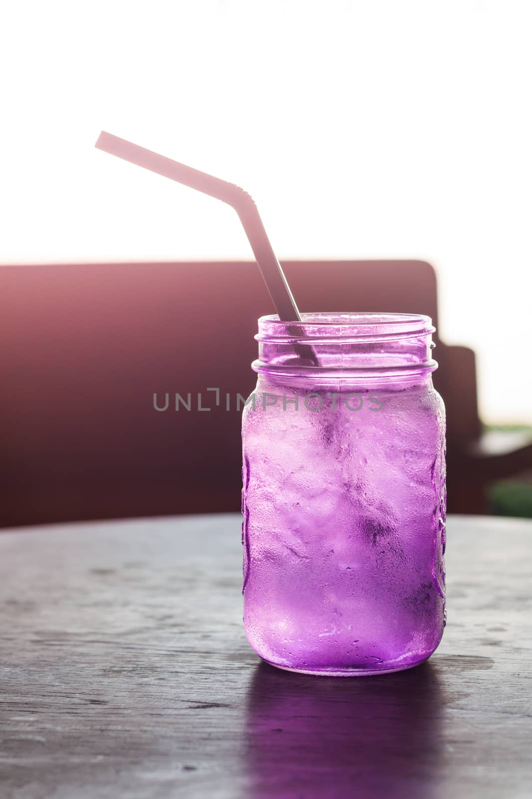 Iced drink in violet glass in coffee shop with vintage filter, stock photo