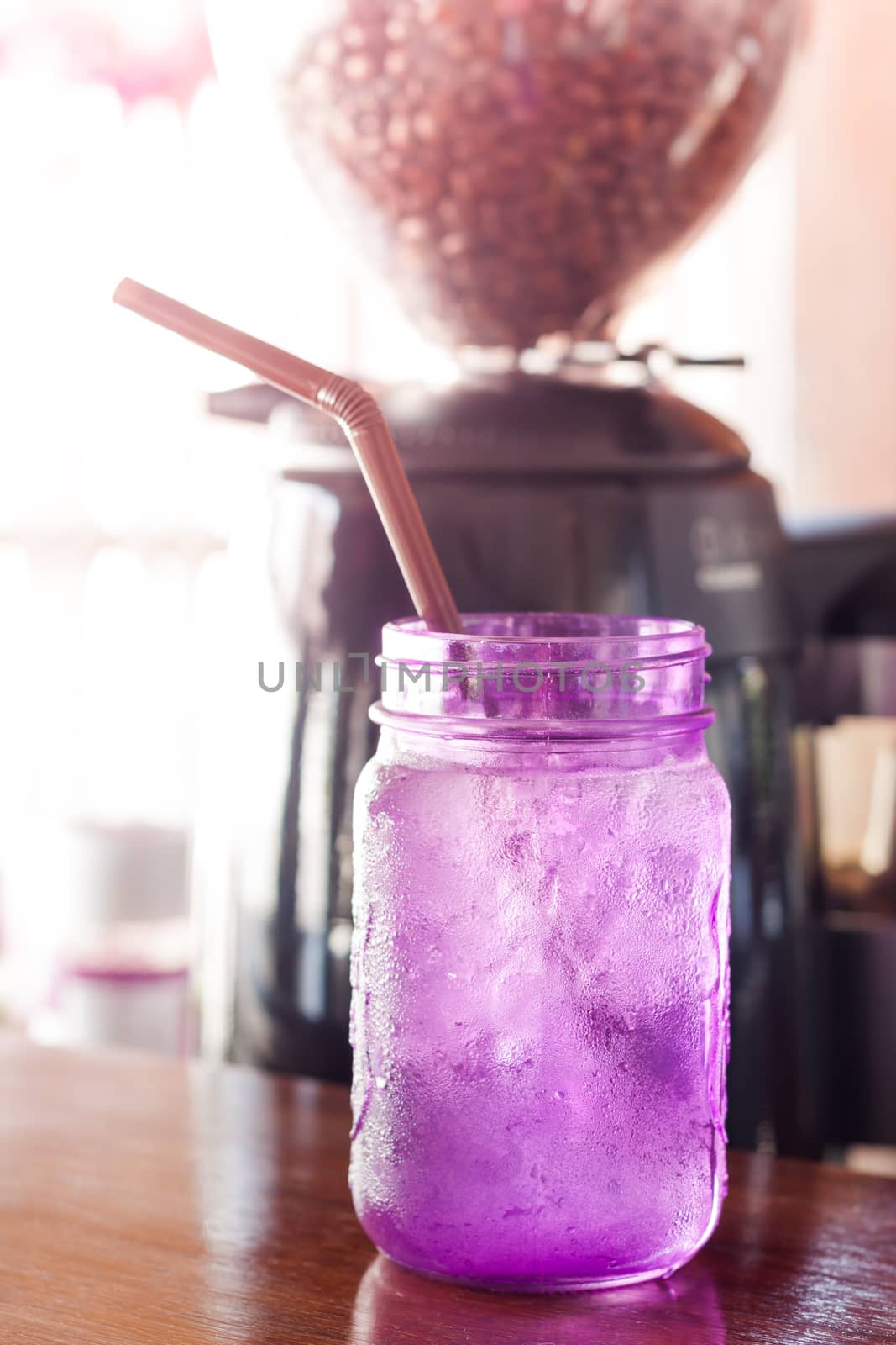 Iced drink in violet glass in coffee shop with vintage filter, stock photo