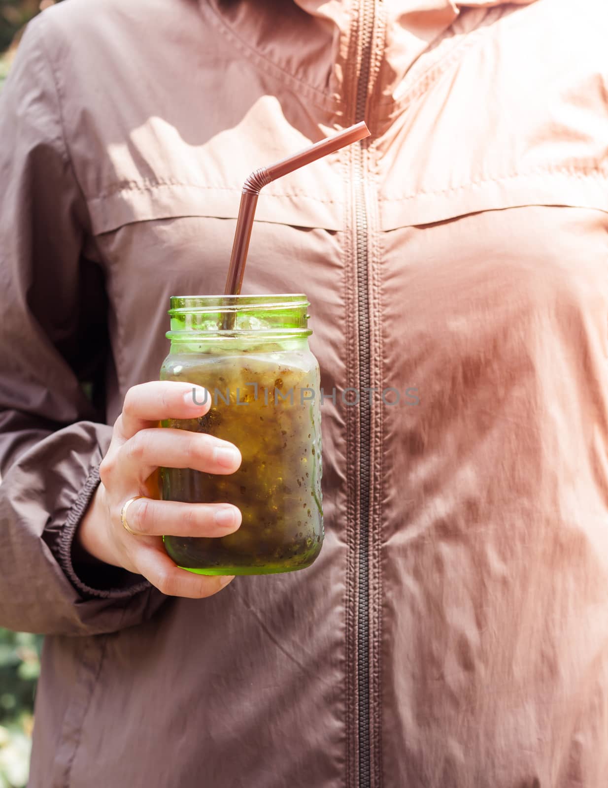 Woman hand holding iced soda in green glass by punsayaporn