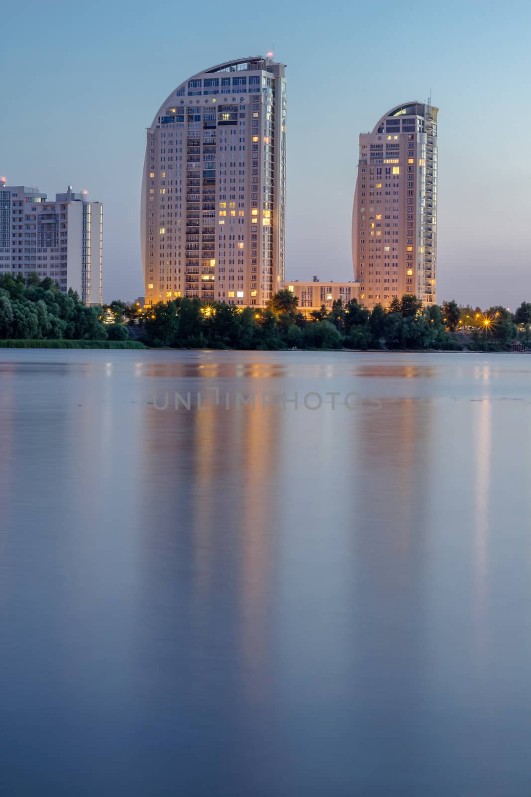 Night city buildings reflected in river water. HDR