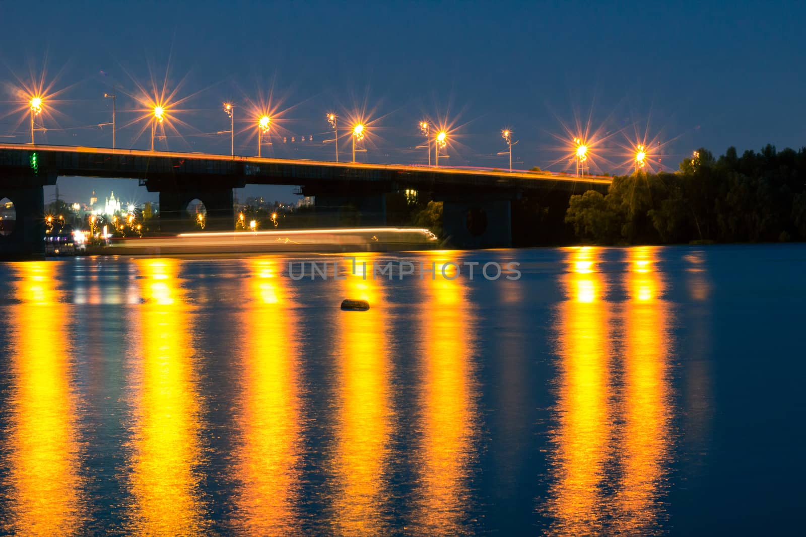 Night bridge lights reflected in river water