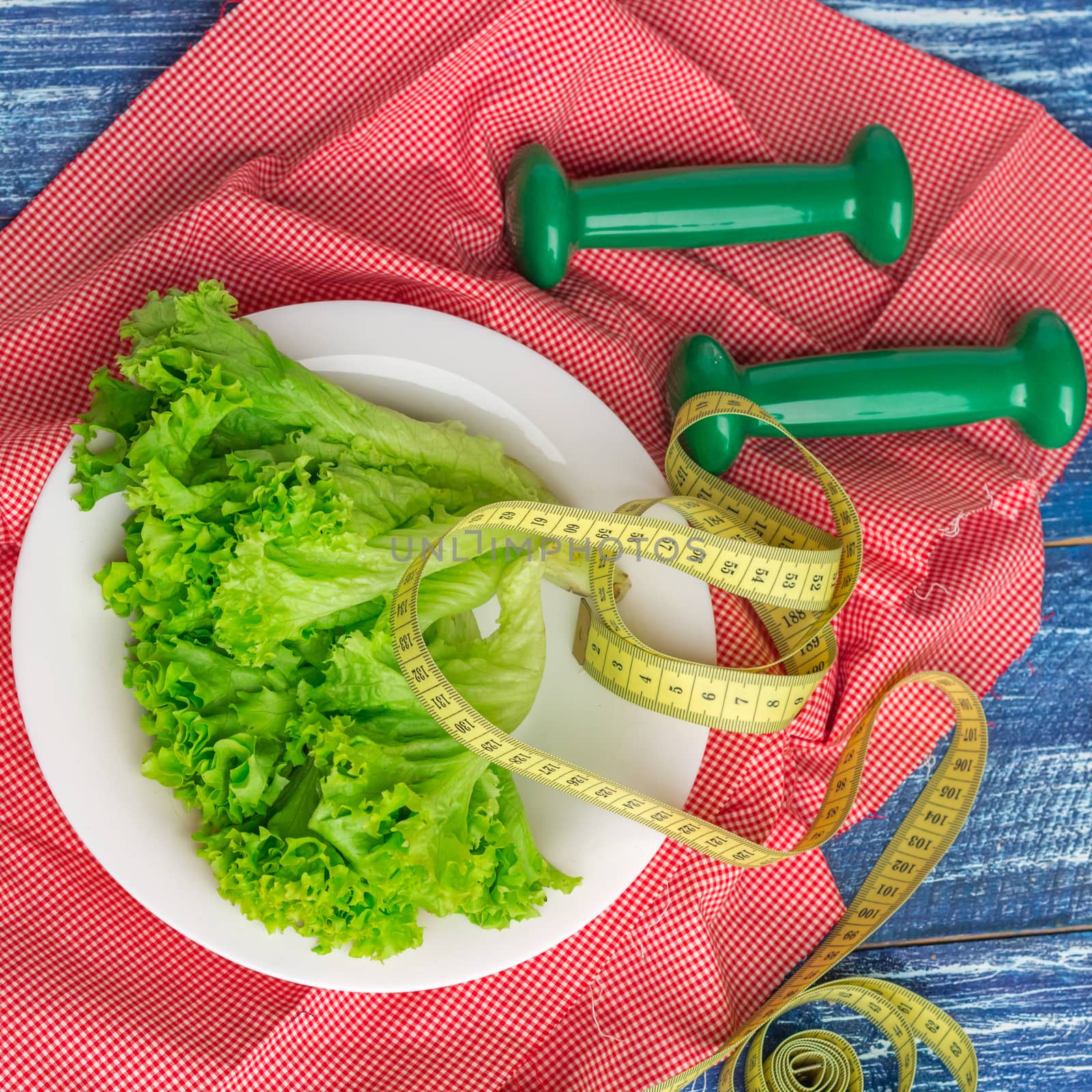 Fitness composition of green lettuce, weights and ruler by VeraVerano