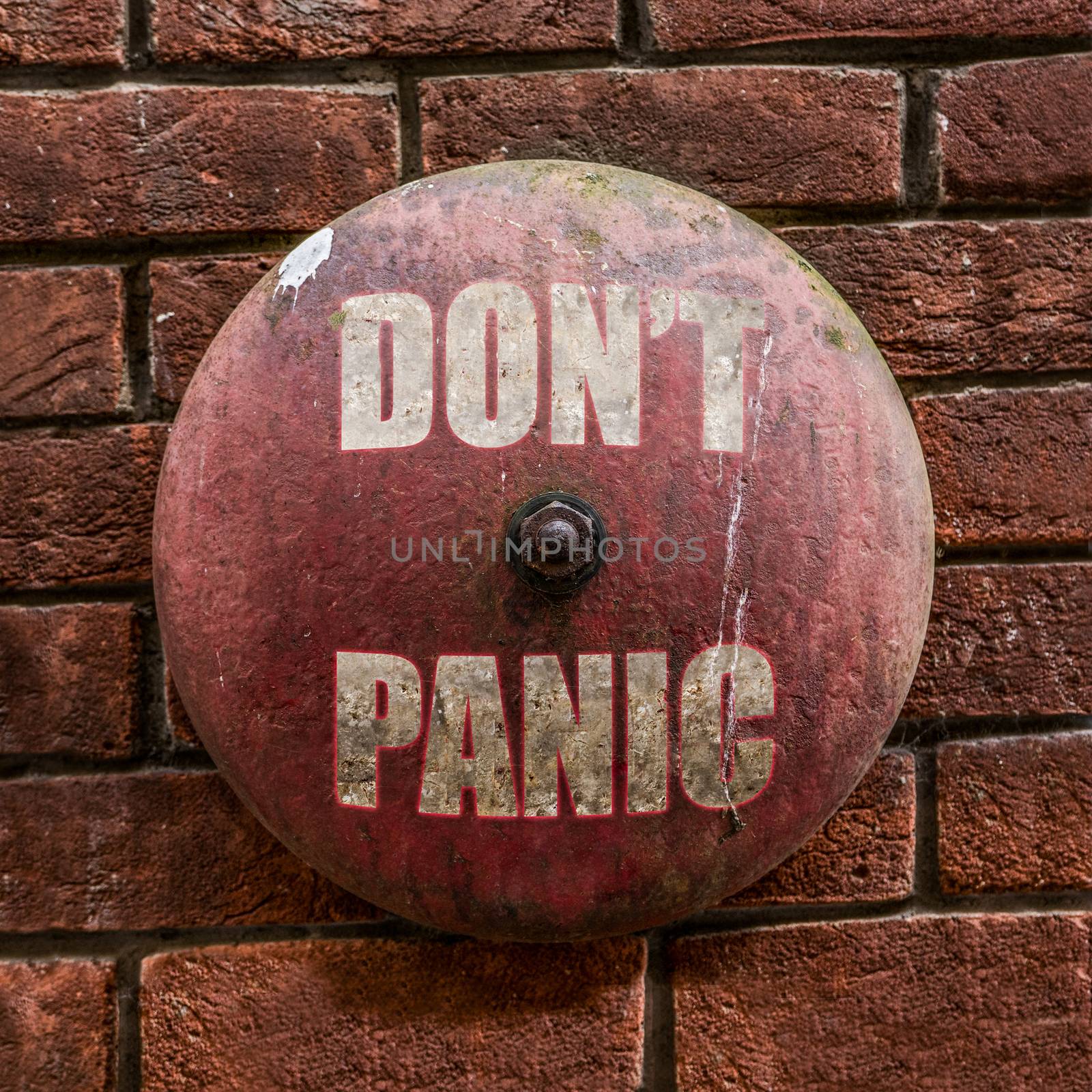 Isolated Rustic Vintage Red Alarm Bell With The Words Don't Panic In White Against A Red Brick Wall