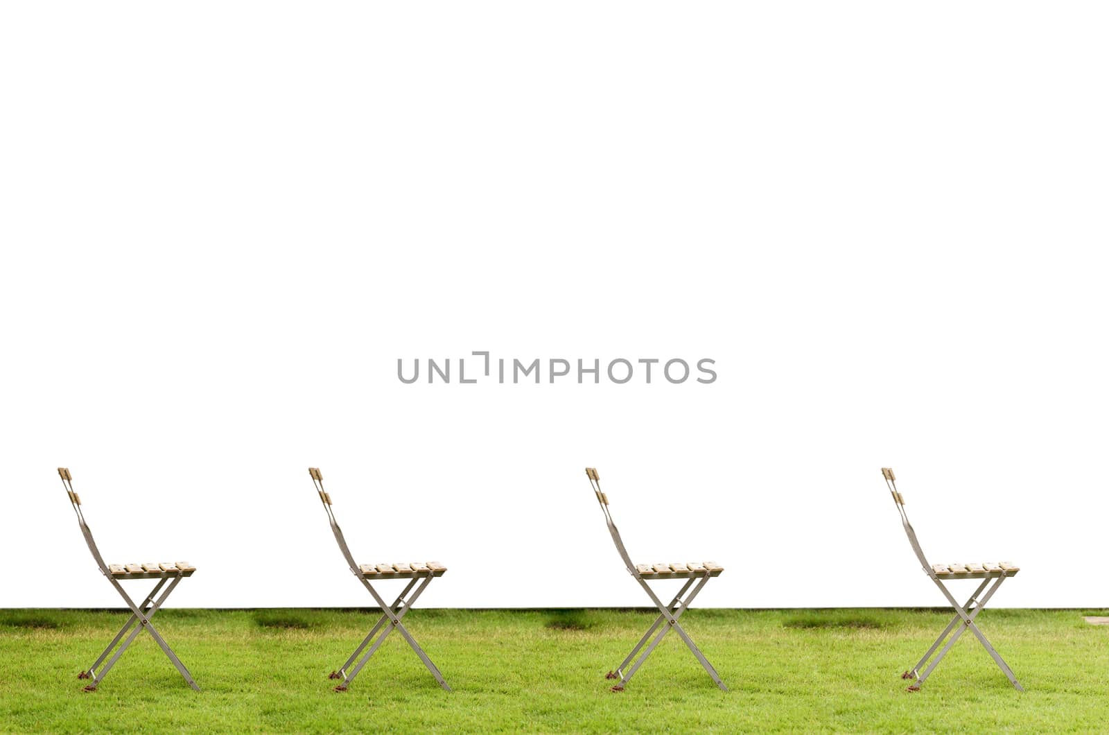 Old chair on green grass in white walll background